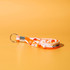 An orange and white stress reliever key chain featuring poppable buttons and a metal keyring.