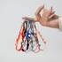 A hand holding multiple Popper Stress Reliever Key Chains in various bright colours. The keychains include a variety of playful designs.