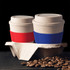 A drink bottle featuring two reusable coffee cups in red and blue, placed in a cardboard holder with coffee beans.