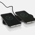 A sleek black dual wireless charger with two smartphones displaying charging indicators.