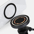 A close-up of a black wireless car charger with a copper ring, positioned near a smartphone's charging pad.
