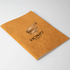 An orange velour notebook with a textured cover and a logo on the front.