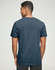 A man is wearing a navy blue premium cotton short-sleeve tee shirt, viewed from the back. The shirt has a logo.