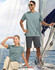 A pair of people wearing a light blue tee shirt on a sailboat, with a logo visible on the shirts.