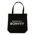A black tote bag with handles, featuring a logo on the front, placed on a wooden table.
