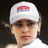 A white cap with a structured front panel and a logo, worn by a woman with a neutral expression.