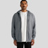 A man stands wearing a grey zip-up hoodie with a hood and kangaroo pockets. The hoodie has a logo on it.
