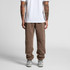 Brown track pants with a relaxed fit, featuring tapered legs and elastic cuffs. The model wears a plain white t-shirt.