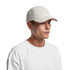A plain cream-coloured Nylon cap worn by a model, featuring a curved brim and a logo.