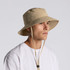 A nylon wide brim bucket hat in beige, featuring an adjustable chin strap and detailing around the brim.