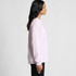 A long-sleeve t-shirt in light pink, featuring a simple design and a logo on the front.