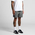 Swim shorts in grey, featuring a logo, styled with a white t-shirt and black athletic shoes.