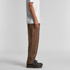 Cord pants in brown, displayed from the side on a model wearing a white T-shirt and black shoes.