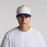 A two-tone cap featuring a cream front and blue peak, worn by a model in a white t-shirt.