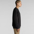 A black jumper is displayed on a model in profile view, showcasing its simple design and fit.