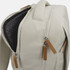 A cream-coloured backpack featuring dual zippers and a textured interior lining. It has a logo on the exterior.