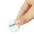 A white circular item tracker is held between fingers, featuring a logo on one side.
