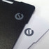 A carbon Bluetooth tracker featuring a black and a white side, both with branding logos.