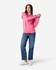 A woman in a pink Gildan Softstyle adult sweatshirt and blue jeans, adjusting her sleeve. The sweatshirt has a logo.