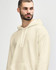 A man wearing a cream-coloured Gildan Softstyle adult hooded sweatshirt, styled with denim jeans and a relaxed pose.