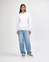 A unisex hooded sweatshirt in white, featuring a front pocket and a plain design. The model wears casual light blue jeans.