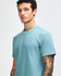 A teal unisex pique mockneck t-shirt with short sleeves, featuring a logo on the front.