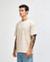 A beige super heavyweight T-shirt displayed on a model, featuring a relaxed fit and short sleeves.