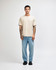 A light beige super heavyweight T-shirt worn by a male model, paired with light blue jeans and sneakers.