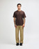 A model wears a brown American Apparel Super Heavyweight T-Shirt paired with olive green cargo pants and sneakers.