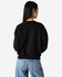 A black women's crewneck sweatshirt with a relaxed fit, viewed from the back. Features a logo on the garment.