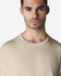 A light beige men's t-shirt displayed on a model, featuring a crew neckline and a simple design.