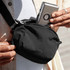 A black Bellroy Lite Belt Bag being held by a person, with a phone partially visible in an outer pocket.