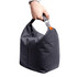 A hand holds a grey patterned cooler bag with a strap. The bag is compact and features a logo.