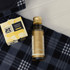 A bottle of olive oil with a gold cap and a box of quince paste on a checkered blanket.