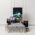 A gourmet gift pack featuring assorted food items, a stylish grey throw, and a bottle, all presented in a black box.