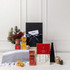A customised gift set featuring festive treats, a grey throw, decorative items, and a black box with a ribbon.