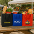 Three insulated grocery totes in black, blue, and red, filled with various groceries including fruits, vegetables, and a drink bottle.