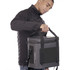 A cooler bag in grey is being held by a person wearing a black jacket, featuring a logo on the side.