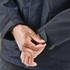 A close-up of a person adjusting the cuff of a dark navy jacket featuring a logo.