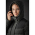 A women's parka in dark green and black with a hood, featuring a close-up of a model adjusting it.