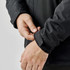 A close-up of a black men's jacket with adjustable wrist cuffs and a logo on the sleeve.