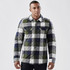 A men's shacket in a quilted, navy, green, and grey plaid pattern with front pockets and a collar.