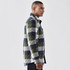 A men's quilted shacket in green, navy, and grey check pattern, featuring a logo on the front.