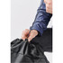 A black backpack with a drawstring closure being pulled tight by a hand. The material appears durable and lightweight.