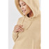 A beige women's fleece pullover hoody with a large hood and drawstring details. The model has a relaxed expression.