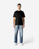 A black Gildan Softstyle adult t-shirt on a male model, paired with light blue jeans and white shoes.