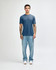 A man wearing a blue American Apparel Tri-Blend T-Shirt paired with light blue jeans and white sneakers.
