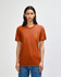 A model wearing an orange American Apparel tri-blend t-shirt, standing against a neutral background.