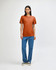 A model wearing an orange American Apparel Tri-Blend T-Shirt paired with blue jeans. The shirt has a logo.