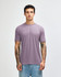 A man wearing a purple American Apparel tri-blend T-shirt paired with light blue jeans, featuring visible tattoos on his arms.